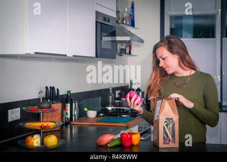 Junge Frau steht in der Küche und lesen das Paket für Anweisungen Stockfoto