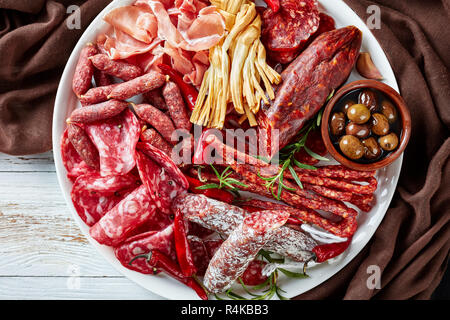 Ansicht von oben Der spanische Wurst und Wurstwaren - jamon, chistorra, Chorizo, salchichon, fuet, Oliven, Rosmarin, chili peppers auf einer Plat Stockfoto