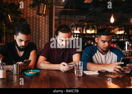 Social Media sucht Konzept. Gemischten rennen Freunde ihre Telefone in der Lounge Bar. Einsamkeit unter Freunden. 1001 Kerle mit smarphones Stockfoto