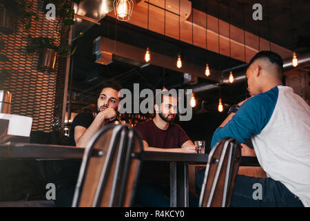 Gruppe von gemischten Rennen junge Männer, die in der Lounge Bar. Multirassischen Freunden verbringt Zeit im Cafe Kaffee trinken Stockfoto