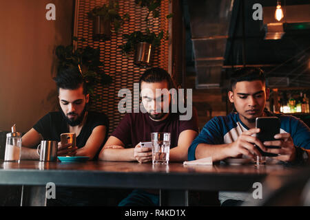 Social Media sucht Konzept. Gemischten rennen Freunde ihre Telefone in der Lounge Bar. Einsamkeit unter Freunden. 1001 Kerle mit smarphones Stockfoto