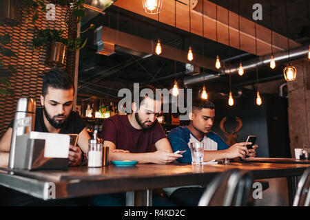 Social Media sucht Konzept. Gemischten rennen Freunde ihre Telefone in der Lounge Bar. Einsamkeit unter Freunden Stockfoto