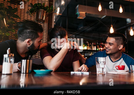 Gerne arabische junge Männer hängen in loft Café. Gruppe von gemischten rennen Leute Spaß in der Lounge Bar. Freunde Chillen und Lachen Stockfoto