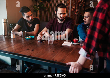 Arabische Freunde ihre Bestellung mit Kellnerin im Restaurant diskutieren. Die Wahl Essen zu bestellen. Cafe und Restaurant Service und Gastfreundschaft Stockfoto