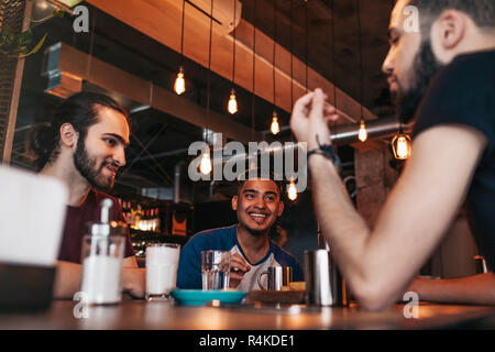 Gerne arabische junge Männer hängen in loft Café. Beste Freunde sprechen in der Lounge Bar. Freunde Chillen und Entspannen Stockfoto