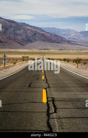 Lange, gerade Straße durch karge Landschaft im Death Valley, Kalifornien, USA führenden Stockfoto