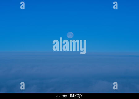 Vollmond am Morgen gesehen aus einem Flugzeug fliegen über der Wolkendecke. Bank von Wolke von in der Morgendämmerung Stockfoto