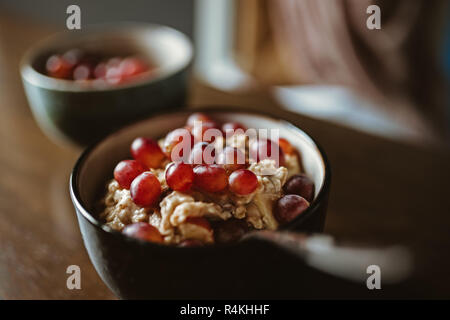 Zwei Schalen mit Porridge mit Trauben auf einem Holztisch Stockfoto