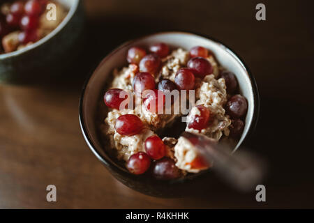 Zwei Schalen mit Porridge mit Trauben auf einem Holztisch Stockfoto