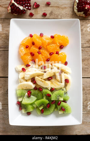 Salat Scheiben von verschiedenen Früchten und Granatapfel Samen auf einer hölzernen Hintergrund. Stockfoto