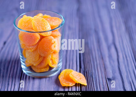 Closeup Schuß aus transparentem Glas gefüllt mit Haufen Sweet Orange getrocknete Aprikosen auf hölzernen Tisch Stockfoto