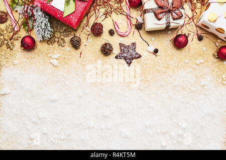 Schöne Weihnachten rot deco Spielereien mit Geschenken auf goldenen Glitzer Hintergrund mit Pulverschnee. Flach Design. Kopieren Sie Platz. Horizontale. Stockfoto