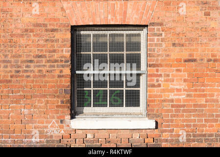 Alte hölzerne Schiebefenster mit Metall Grill in Red brick wall in der alten Fabrik eingestellt Stockfoto