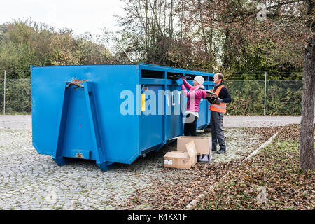 Frau und Mann das Altpapier in Container Recycling center Stockfoto