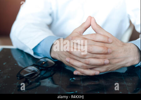 Gefalteten Händen des Arztes liegen auf der Tabelle auf der MRT-Aufnahme Diagnose Stockfoto