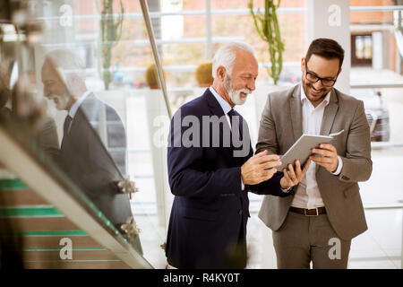 Portrait von älteren Geschäftsmann zeigen und etwas zeigen, junior Partner auf digitalen Tablet im Büro Stockfoto