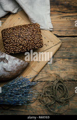Gebackene hausgemachte Roggen dunkles Brot mit Koriander und Lavendel auf rustikalen Holztisch Hintergrund. Stockfoto