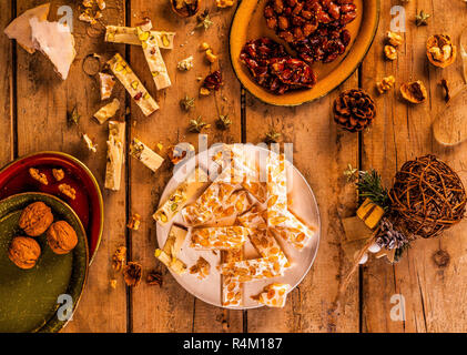 Nougat und Weihnachtsschmuck auf einem Holztisch. Ansicht von oben. Stockfoto