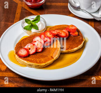 Dicken, Schwammigen amerikanische Pfannkuchen mit Ahornsirup, Erdbeeren und Sahne. Stockfoto