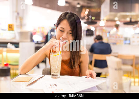 Frau genießen Soft Drink und die Auswahl auf der Speisekarte im Restaurant Stockfoto