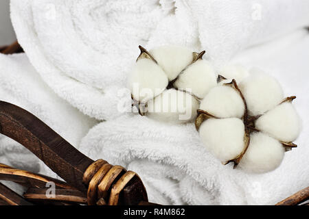 Wäsche Korb flauschigen weißen Handtüchern und Baumwolle boll Blumen. Fokus auf den Vordergrund mit unscharfem Hintergrund. Stockfoto