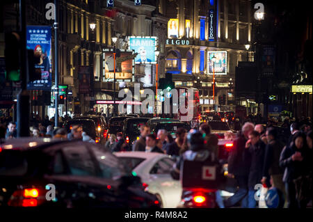 LONDON - Dezember 23, 2018: Fußgänger überqueren ein Verkehr - verstopfte Kreuzung am Piccadilly Circus vor dem leuchtenden Lichter von den Theatern im West End entfernt. Stockfoto