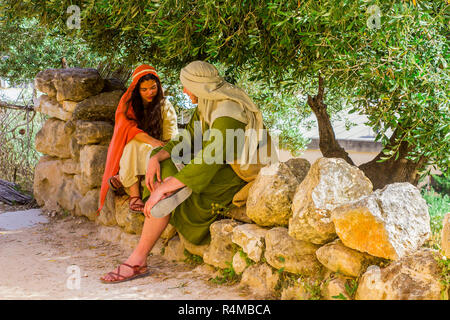 Ein junger Männer und Frauen in Kostümen im Freilichtmuseum von Nazareth Village Israel. Diese Website bietet einen Blick auf das Leben im alten Israel Stockfoto