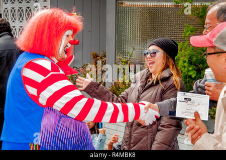 Freut sich Asiatische amerikanische Frau begegnet ein älterer Mann spielt ein Clown auf einem Straßenfest in Laguna Beach, CA. Stockfoto