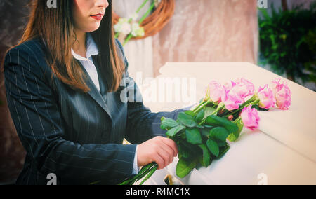 Frau, Rose auf Sarg am Begräbnis Stockfoto