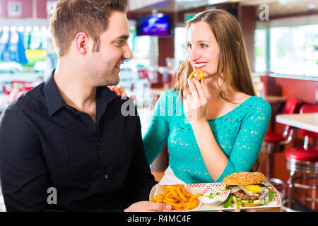 Freunde oder ein Paar essen fast food mit Burger und Pommes frites Stockfoto