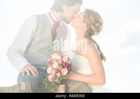 Brautpaar küssen auf Feld nach Hochzeit Stockfoto