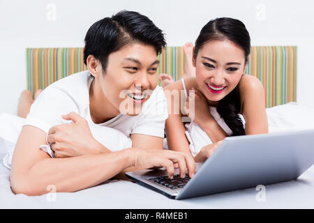 Asiatische Paar im Schlafzimmer das Surfen im Internet mit dem Computer Stockfoto