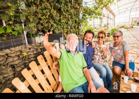 Familie Gruppe von Menschen kaukasischen Senior und Männer mittleren Alters und Frau alle zusammen unter einem selfie Bild mit Handy Technologie auf Soc zu teilen Stockfoto