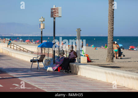 Haar Flechter im Schatten sitzen auf der Strandpromenade, Roquetas de Mar, Almeria, Spanien Stockfoto