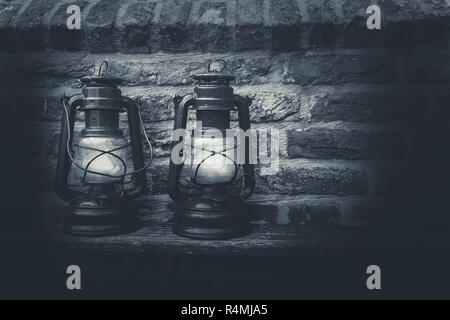 Alte antike Öllampe in der Nacht auf einer hölzernen Oberfläche Schwarz und Weiß Stockfoto