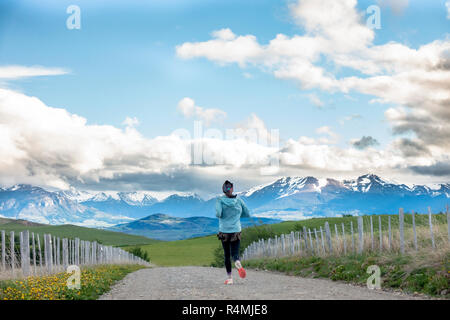 Frau, die auf einem Feldweg mit wunderschönen Bergen im Hintergrund in der Nähe von Coyhaique, Chile in der Region Aysen in der Nähe von Patagonien. Stockfoto