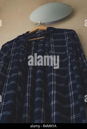 Blaues T-Shirt mit Streifen an der Wand im Wohnzimmer - isoliertes Objekt, teilweise unscharf, Vintage Film bearbeiten Stockfoto