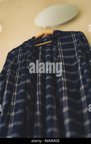 Blaues T-Shirt mit Streifen an der Wand im Wohnzimmer - isoliertes Objekt, teilweise unscharf, Vintage Film bearbeiten Stockfoto