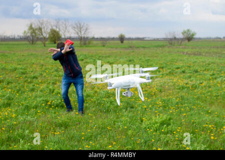 Ein Mann verbirgt sich eine Kollision mit einer Drohne. Quadrocopter fliegt zu der Person Stockfoto