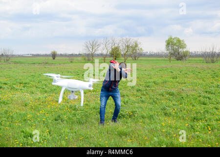 Ein Mann verbirgt sich eine Kollision mit einer Drohne. Quadrocopter fliegt zu der Person Stockfoto