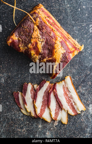 Scheiben geräucherter Speck auf alten Küchentisch. Ansicht von oben. Stockfoto