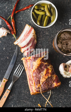 Scheiben geräucherter Speck, Gurken, Paprika, Knoblauch und Bier. Ansicht von oben. Stockfoto