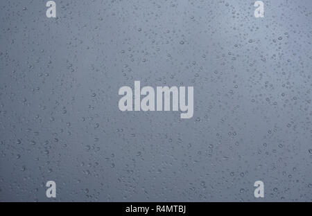 Dark Blue Window Glasoberfläche mit Regen fällt auf. Wasser tropft Textur Hintergrund Stockfoto