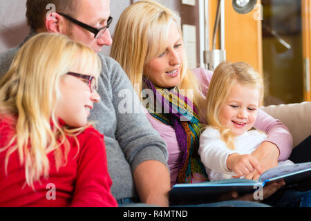 Familie lesen Geschichte im Buch auf dem Sofa zu Hause Stockfoto