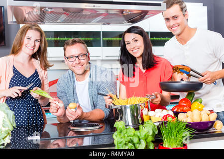 Freunde kochen Pasta und Fleisch in der Küche Stockfoto