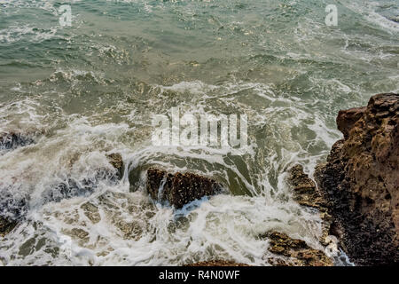 Yarada Strand mit indischen Ozeanwellen, die auf die Uferfelsen und -Steine krachen. Langzeitbelichtung mit seidig glattem Wasser und Felsen im Hintergrund. Stockfoto