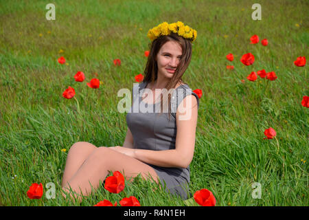 Ein Mädchen mit einem Kranz von Löwenzahn auf dem Kopf. Schönen Fee junge Mädchen in einem Feld zwischen den Blumen Tulpen. Stockfoto