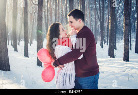 Paar ist umfassend und Holding Bündel Ballone im Winter Forest Stockfoto