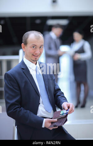 Happy Geschäftsmann öffnet Portemonnaie. Foto auf dem Hintergrund von Office Stockfoto