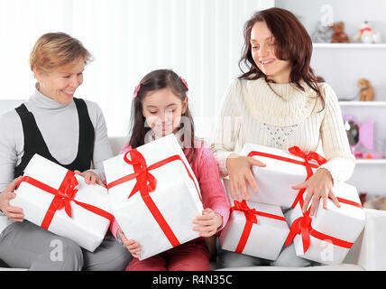 Großmutter, Mutter und Tochter mit geschenkboxen Sitzen auf der Couch. Urlaub Konzept Stockfoto